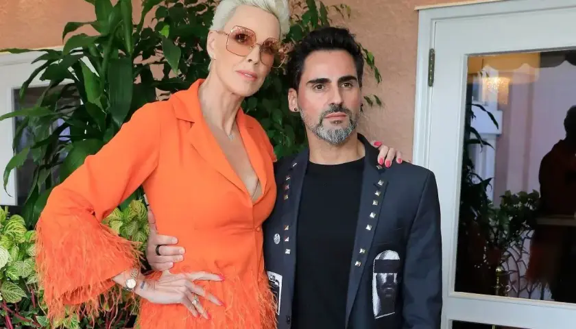 Brigitte Nielsen z mężem, Mattem. Ona w pomarańczowej kreacji z piórami, on w ozdobnej marynarce.