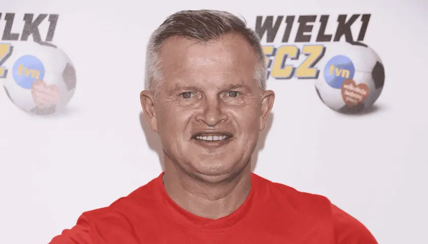 Uśmiechnięty bieleninik z TVN w czerwonej koszulce, na tle piłki nożnej z logo WOŚP.