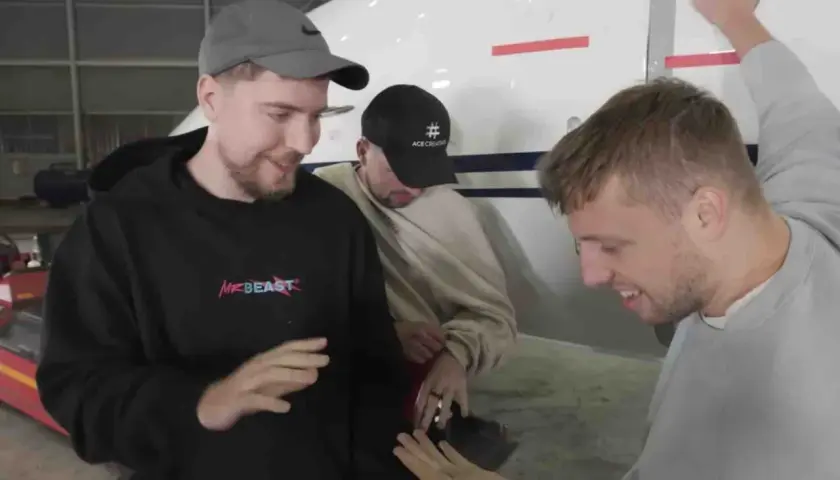 Trzech mężczyzn, w tym MrBeast, stoi obok samolotu. Pytanie "czy Mister Beast żyje" jest nieaktualne, bo widać go w świetnej formie!