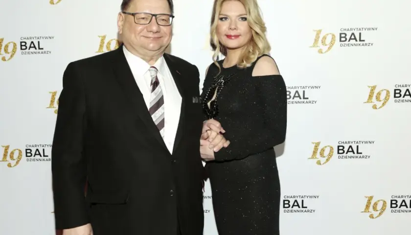 Dominika Lis, w wieku około 40 lat, w czarnej, błyszczącej sukni, stoi obok starszego mężczyzny w garniturze.
