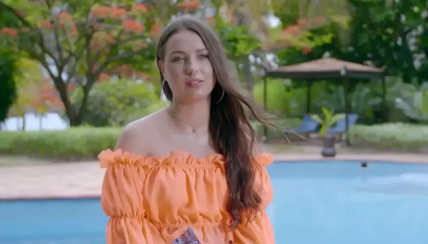 Bogusia w Hotel Paradise, w pomarańczowej bluzce, relaksuje się przy basenie w tropikalnym ogrodzie.
