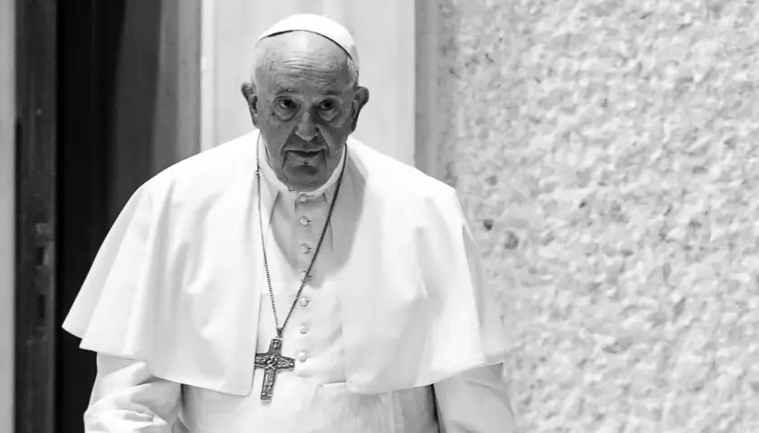 Papież Franciszek, mimo swojego wieku, z uwagą spogląda przed siebie. W białej sutannie i z krzyżem na szyi.