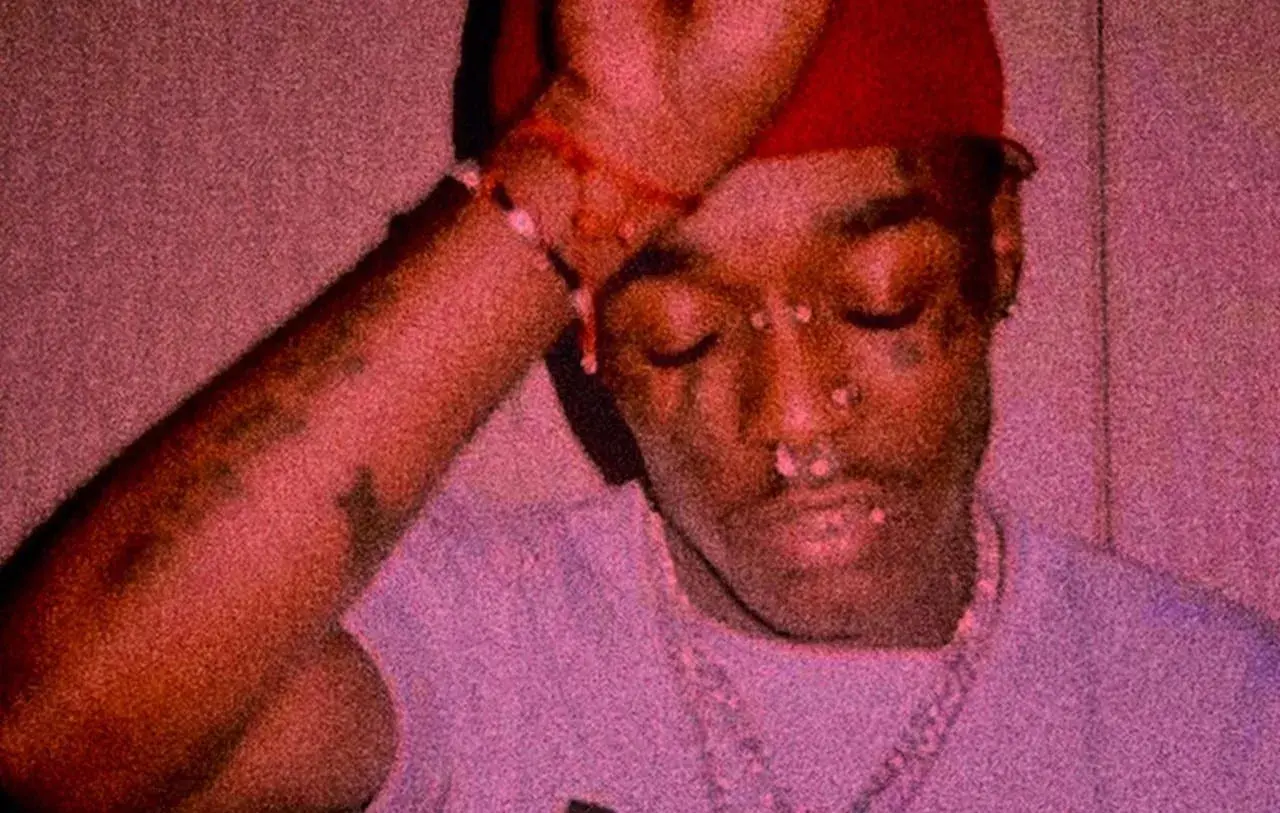 Lil Uzi Vert z diamentem na czole, w czerwonej czapce i z biżuterią.