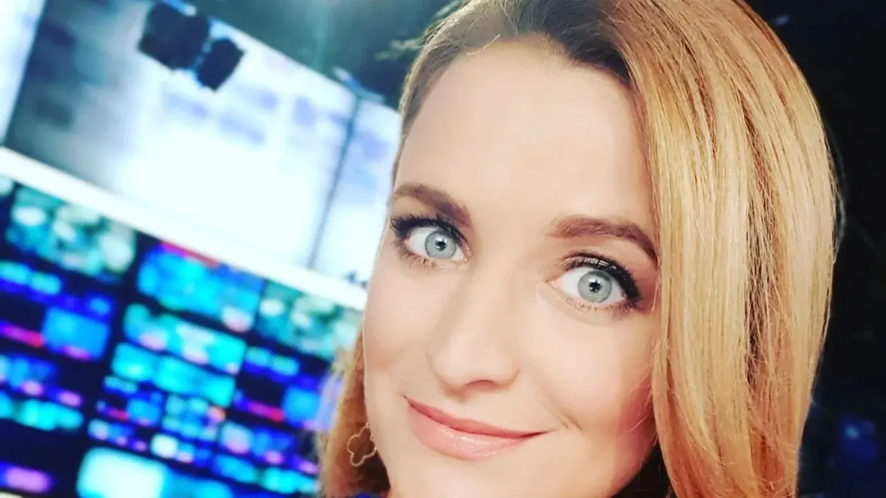 Dagmara Kaczmarek Szalkow z TVN Fakty z błękitnymi oczami i blond włosami, w tle ekrany.