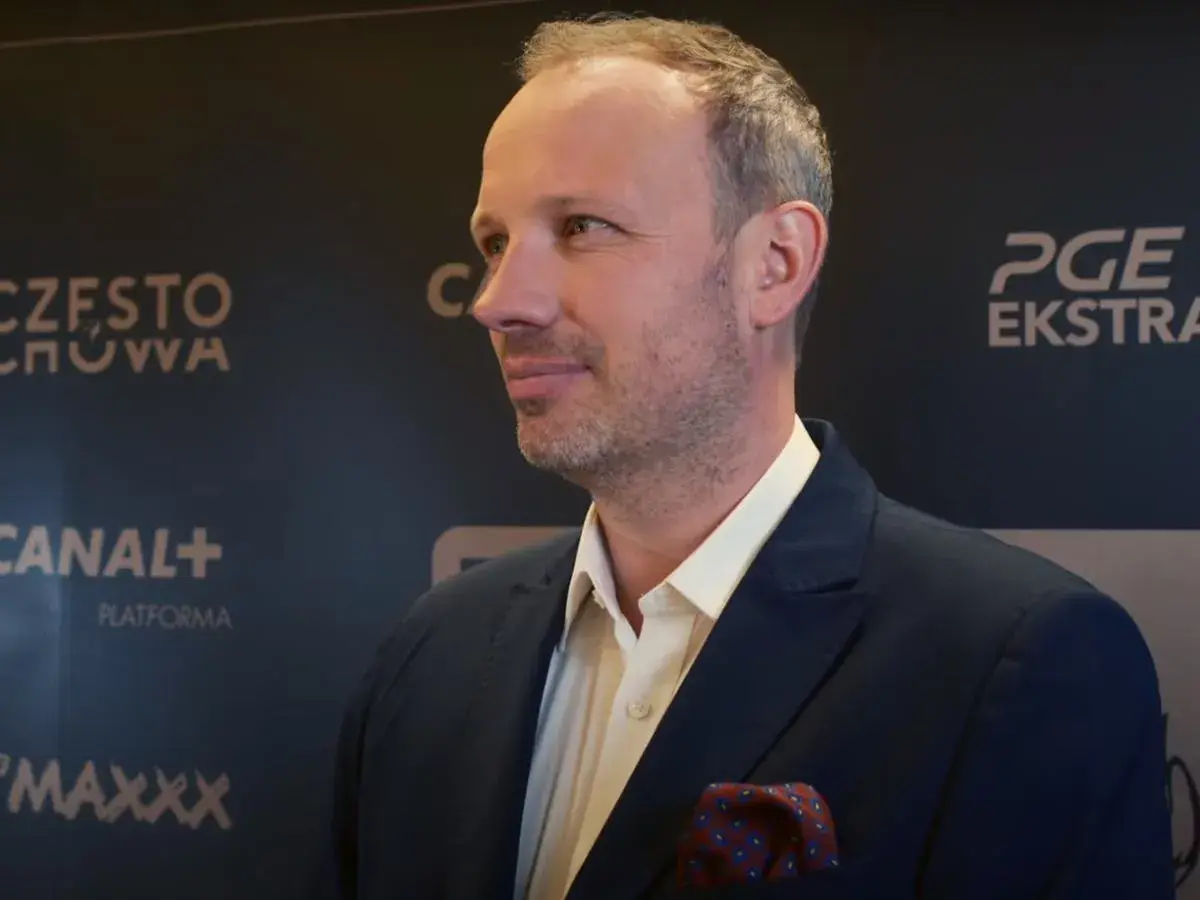 Marcin Majewski z TVN w eleganckim garniturze, na tle logotypów PGE Ekstraklasa i Canal+.