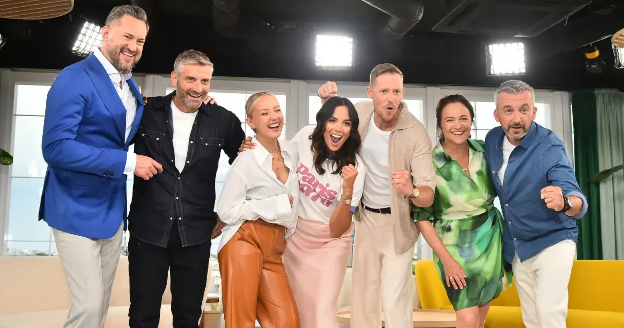 Uśmiechnięci dziennikarze i prezenterzy TVN pozują do zdjęcia, świętując sukces.