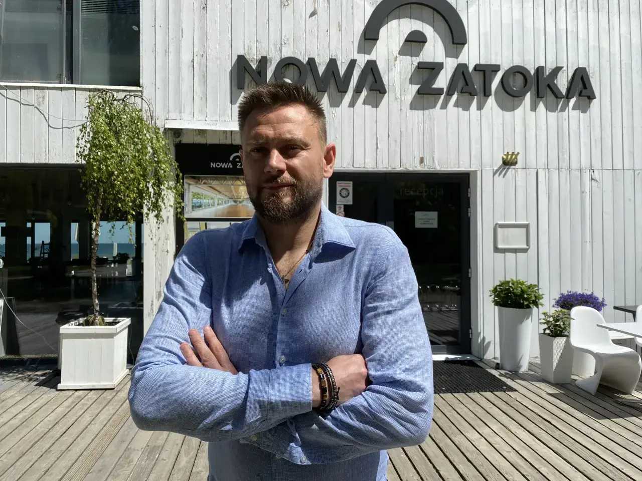 Mężczyzna stoi przed budynkiem z napisem "NOWA ZATOKA".