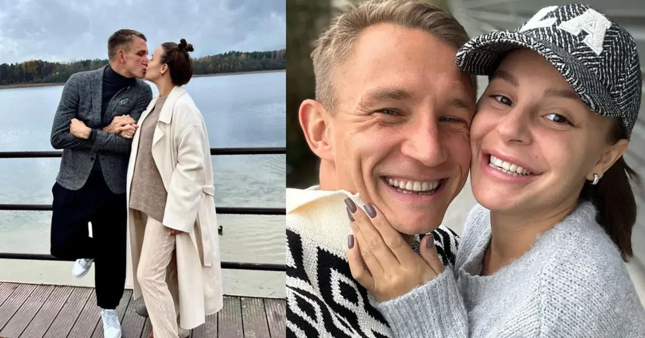 Jakub Rutnicki i jego żona, uśmiechnięci i zakochani, dzielą się czułym pocałunkiem nad jeziorem.