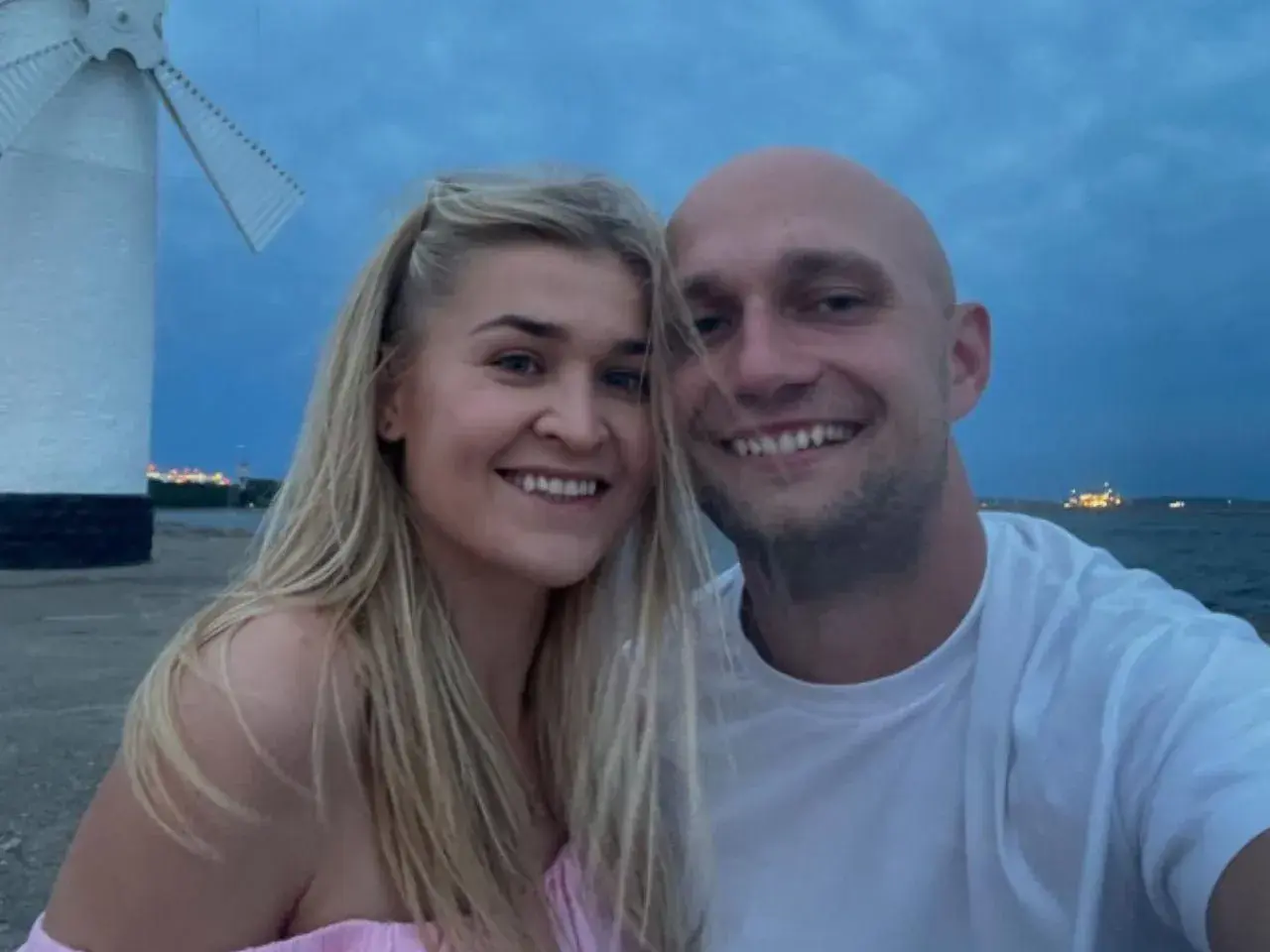 Klaudia z Rolnik szuka żony i jej partner uśmiechają się do zdjęcia na tle morza i wiatraka.