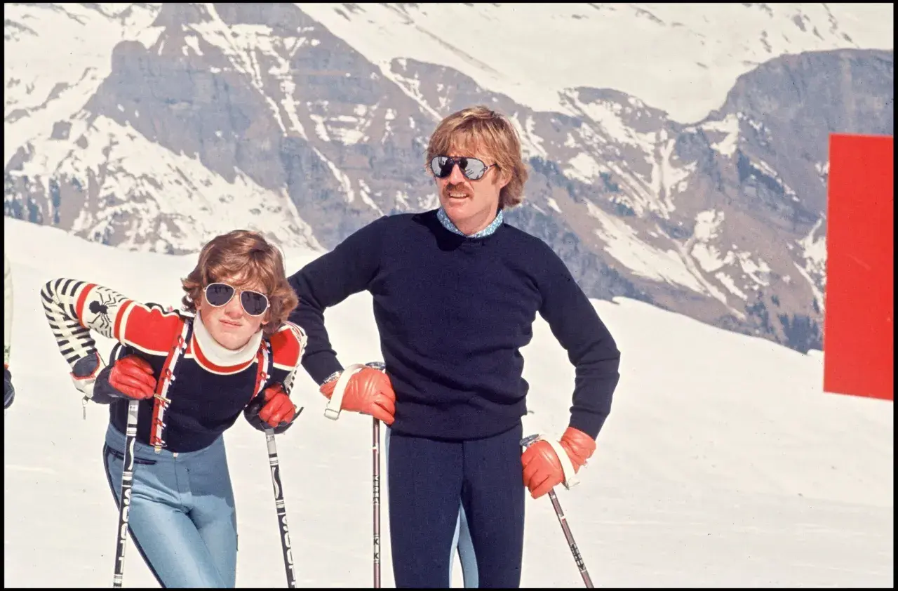 Robert Redford i jego dzieci na stoku narciarskim, w tle ośnieżone góry.