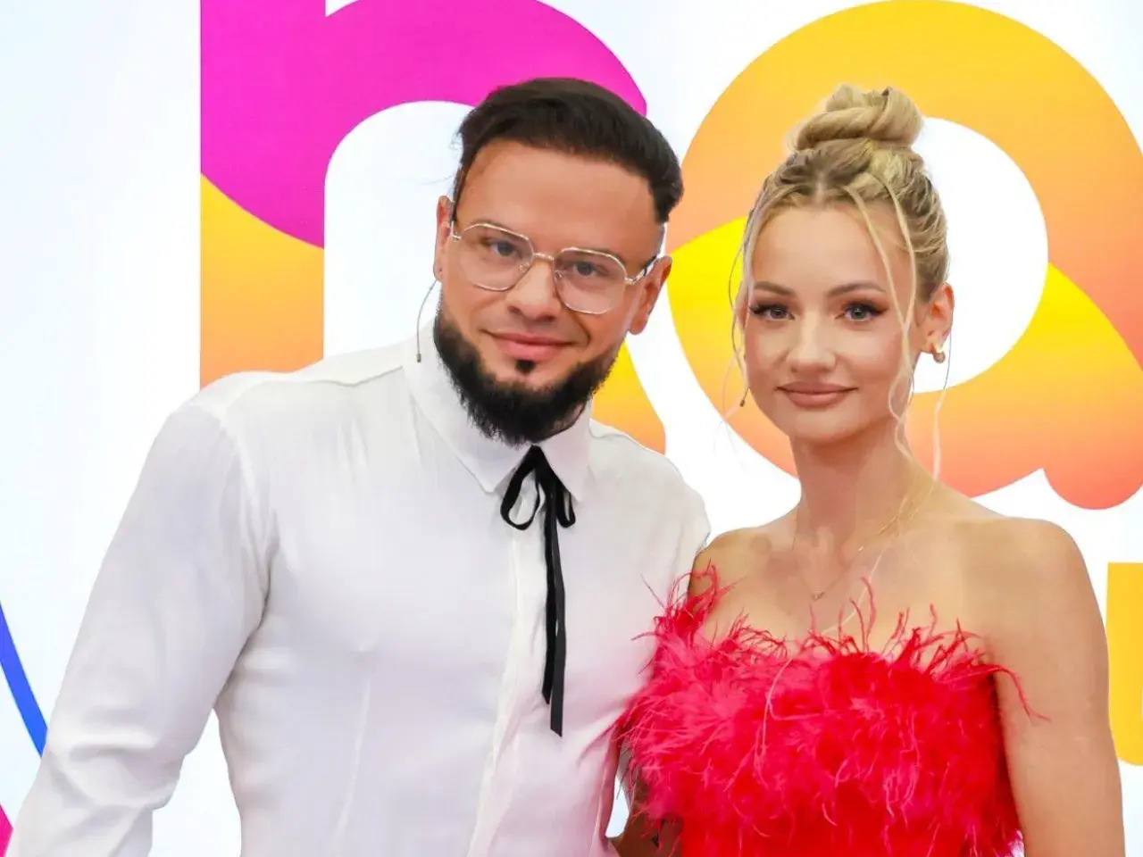 Para fit lovers, ile lat mają? Ona w różowej sukience, on w białej koszuli.