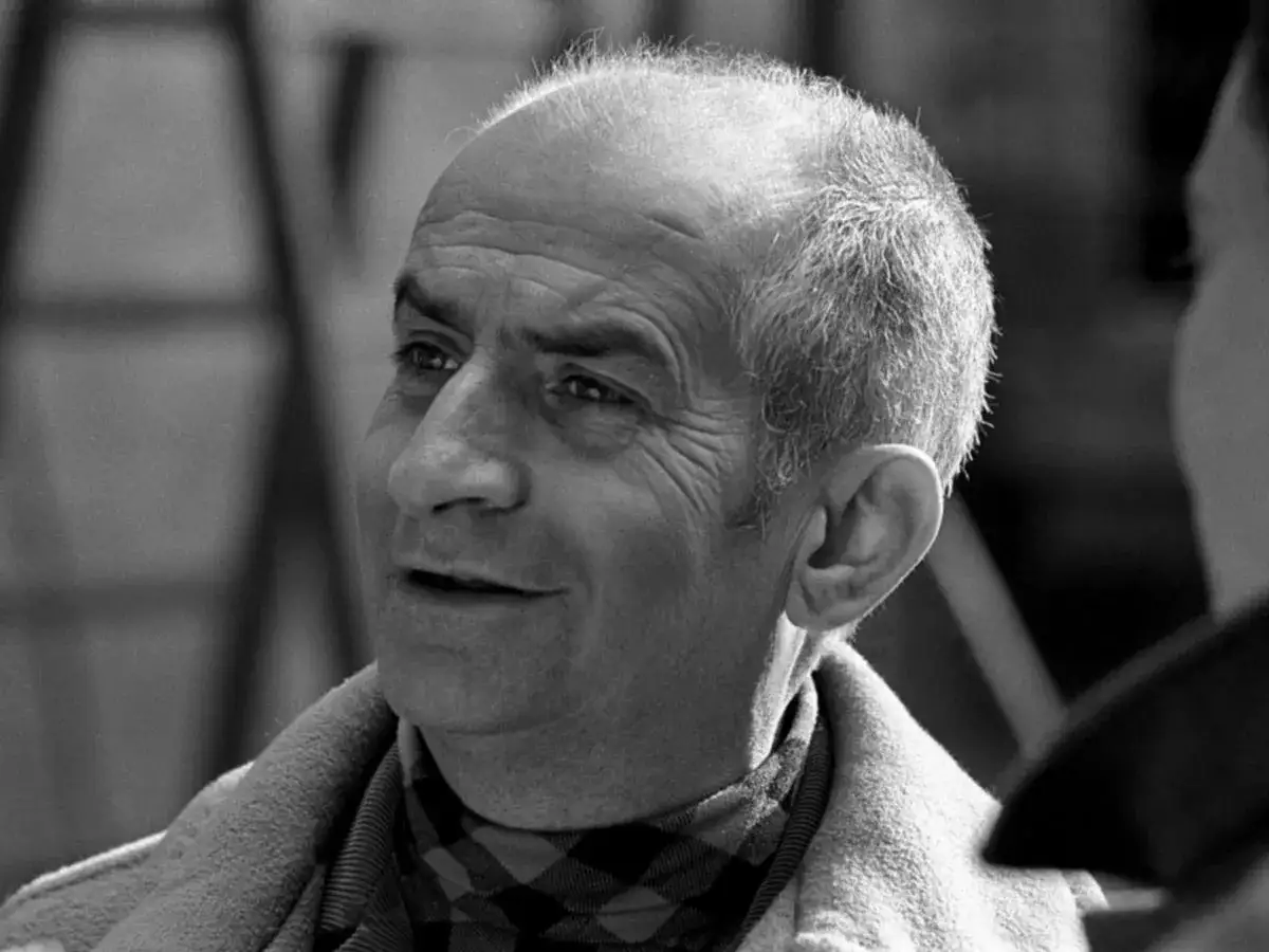 Louis de Funès, zamyślony, w kratkowanym szaliku. Może właśnie opowiadał dowcip swojej żonie?