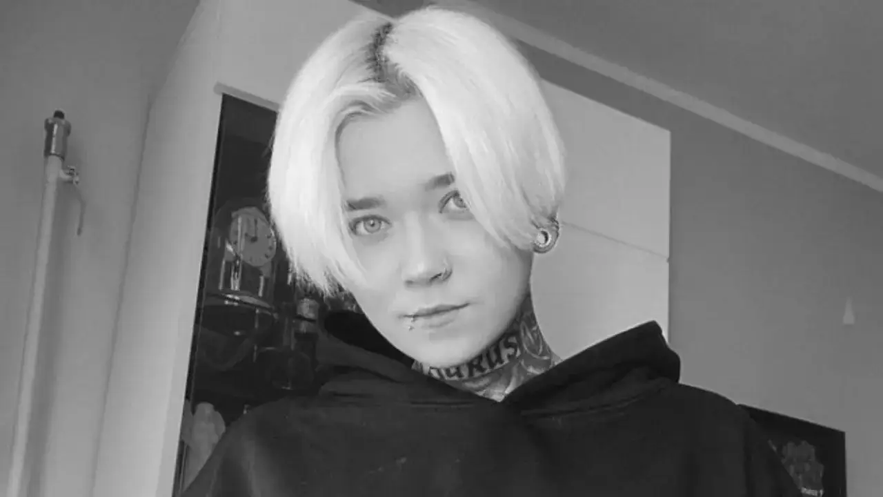 Patrycja Widera, młoda kobieta z blond włosami i tatuażami na szyi, patrzy w obiektyw.