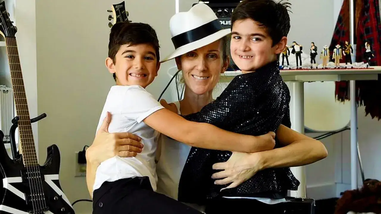 Celine Dion z synami, Eddy i Nelson, w objęciach. W tle gitary i figurki Michaela Jacksona.