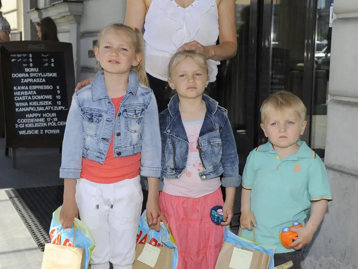 Dominika Chorosińska z dziećmi, trójka uśmiechniętych maluchów z torbami zakupowymi.