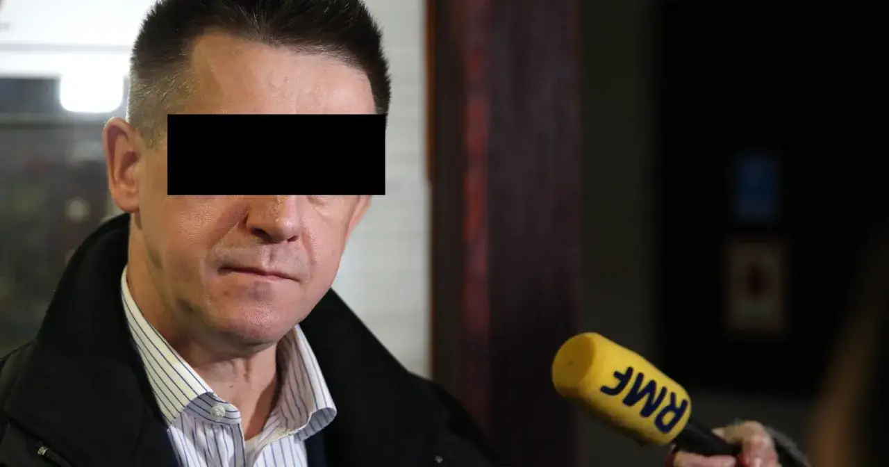 Mężczyzna z zakrytymi oczami, trzymający mikrofon RMF FM, w kontekście afery podkarpackiej.