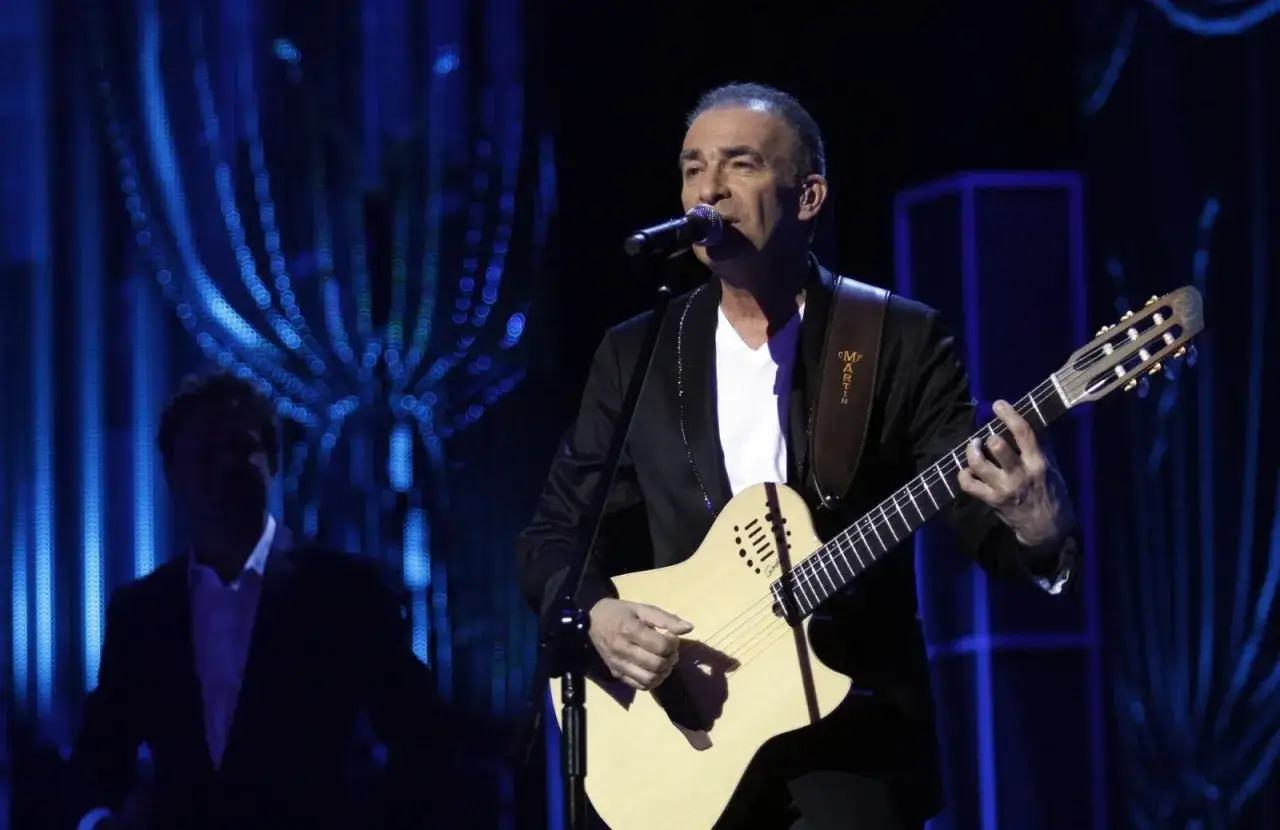 Koncertowy występ Seweryna Krajewskiego, który nie żyje. Artysta gra na gitarze, śpiewając do mikrofonu.
