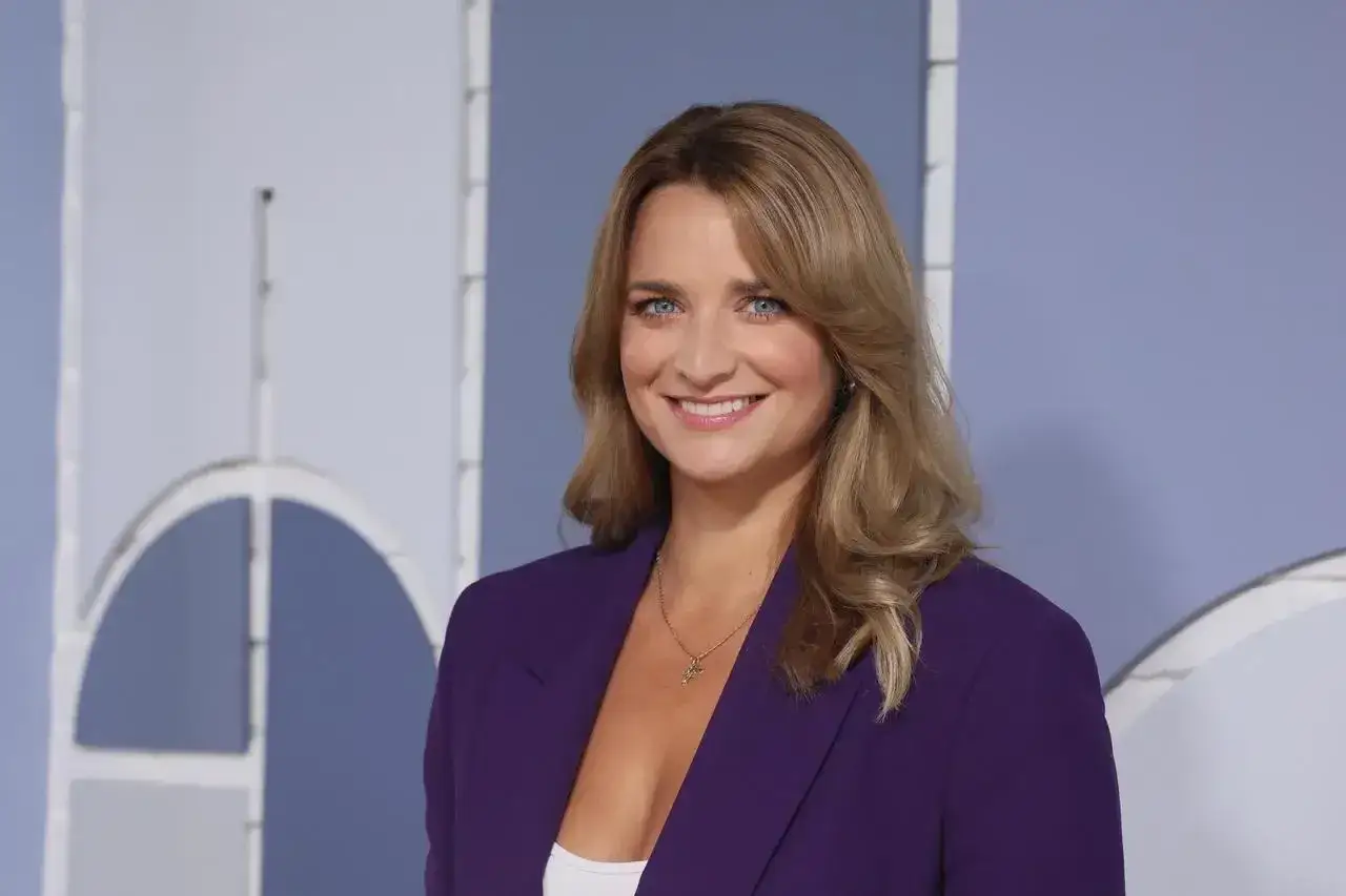Dagmara Kaczmarek Szalkow, prezenterka TVN Fakty, w fioletowej marynarce, uśmiecha się do kamery.