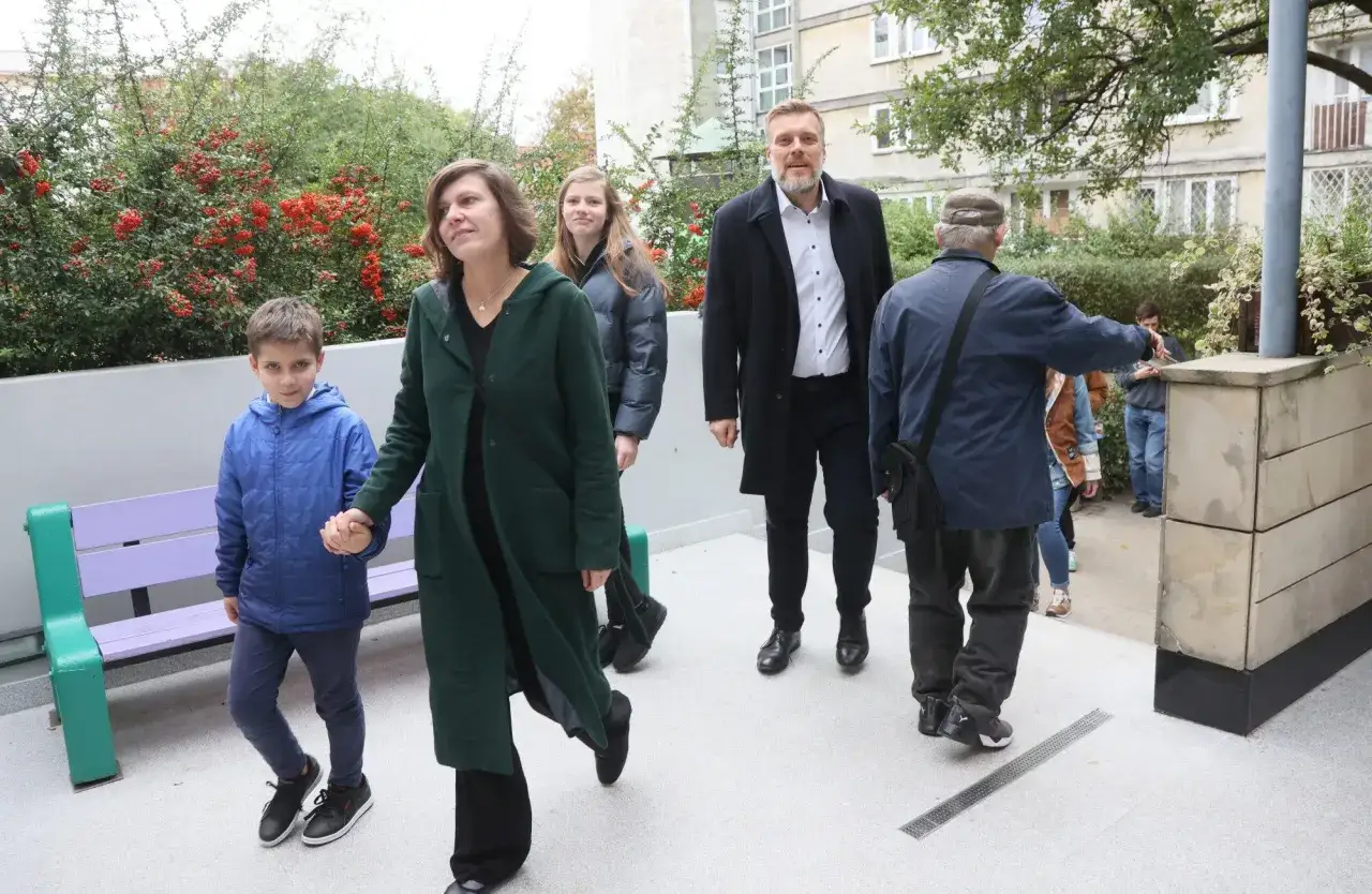 Adrian Zandberg z żoną i dziećmi spacerują. Kobieta w zielonym płaszczu trzyma syna za rękę.