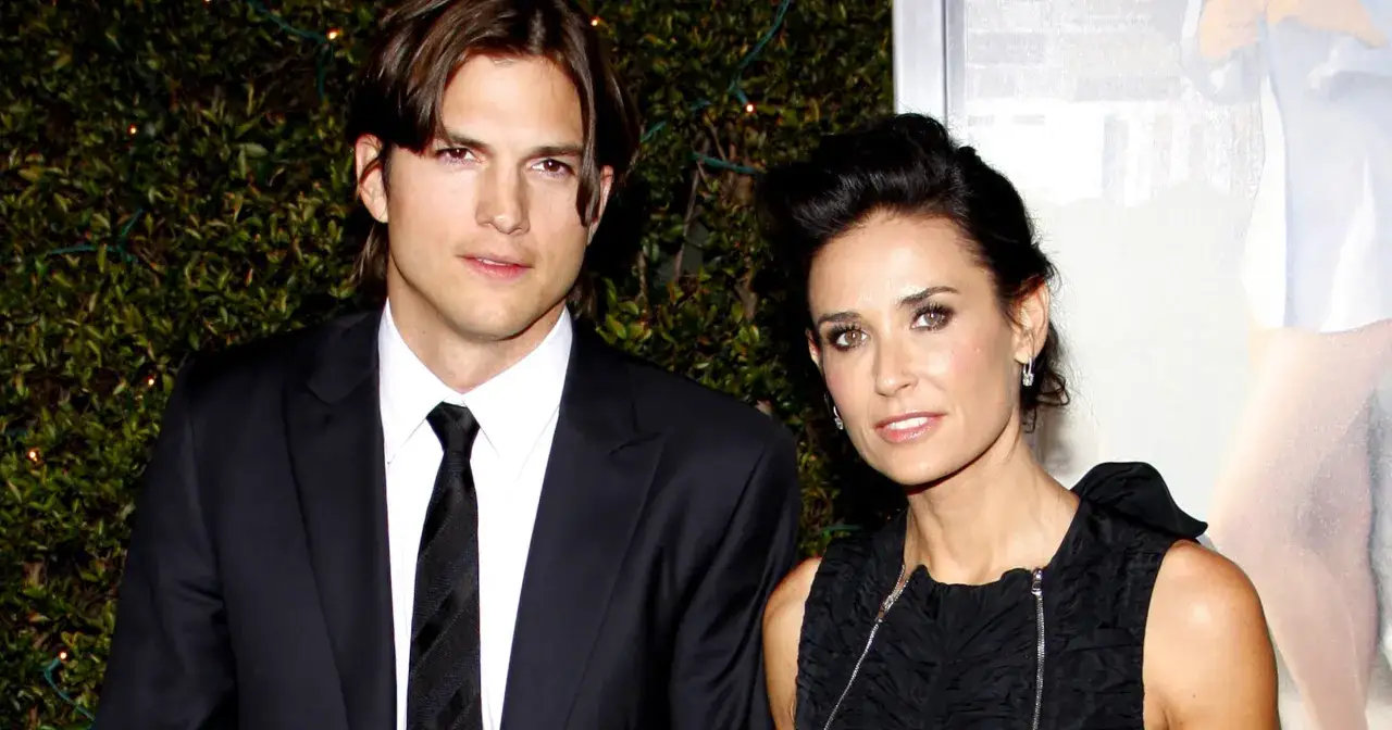 Demi Moore i Ashton Kutcher na czerwonym dywanie, ona w czarnej sukience, on w garniturze.