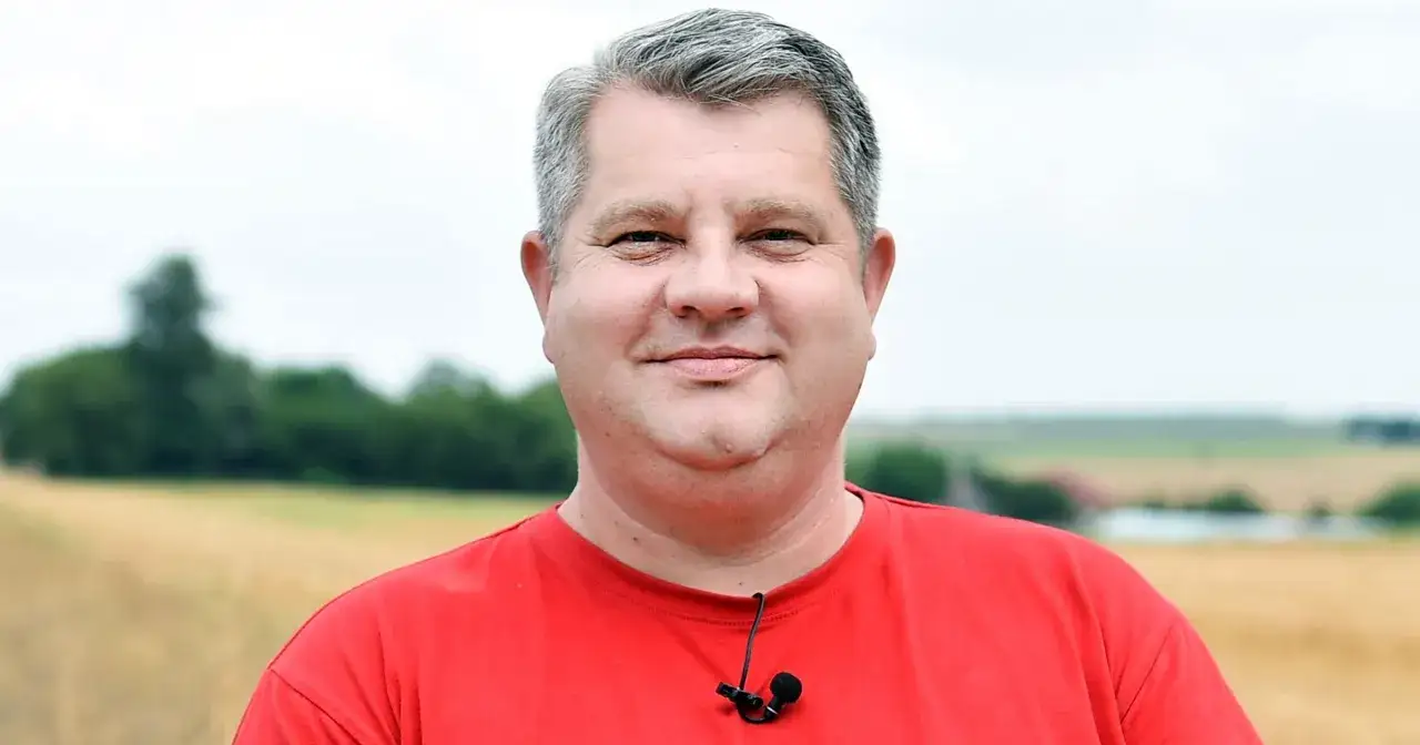 Artur Witkowski, zmagający się z chorobą, uśmiecha się na tle pola.