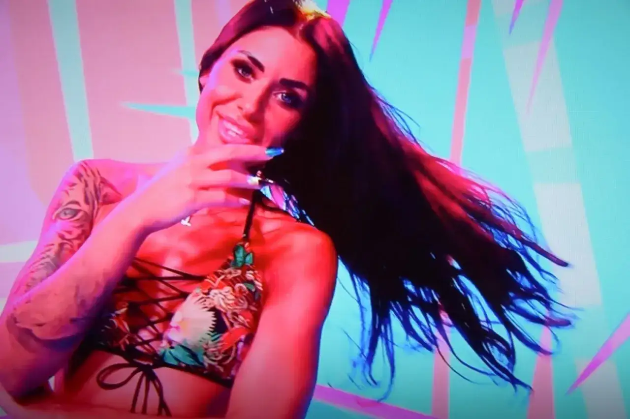 Stella z Love Island w kolorowym bikini, z tatuażem tygrysa na ramieniu, uśmiecha się do kamery.