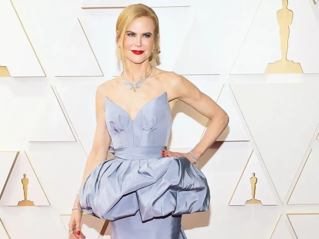 Nicole Kidman w błękitnej sukni na czerwonym dywanie. Jej imponujący wzrost i elegancja przyciągają uwagę.