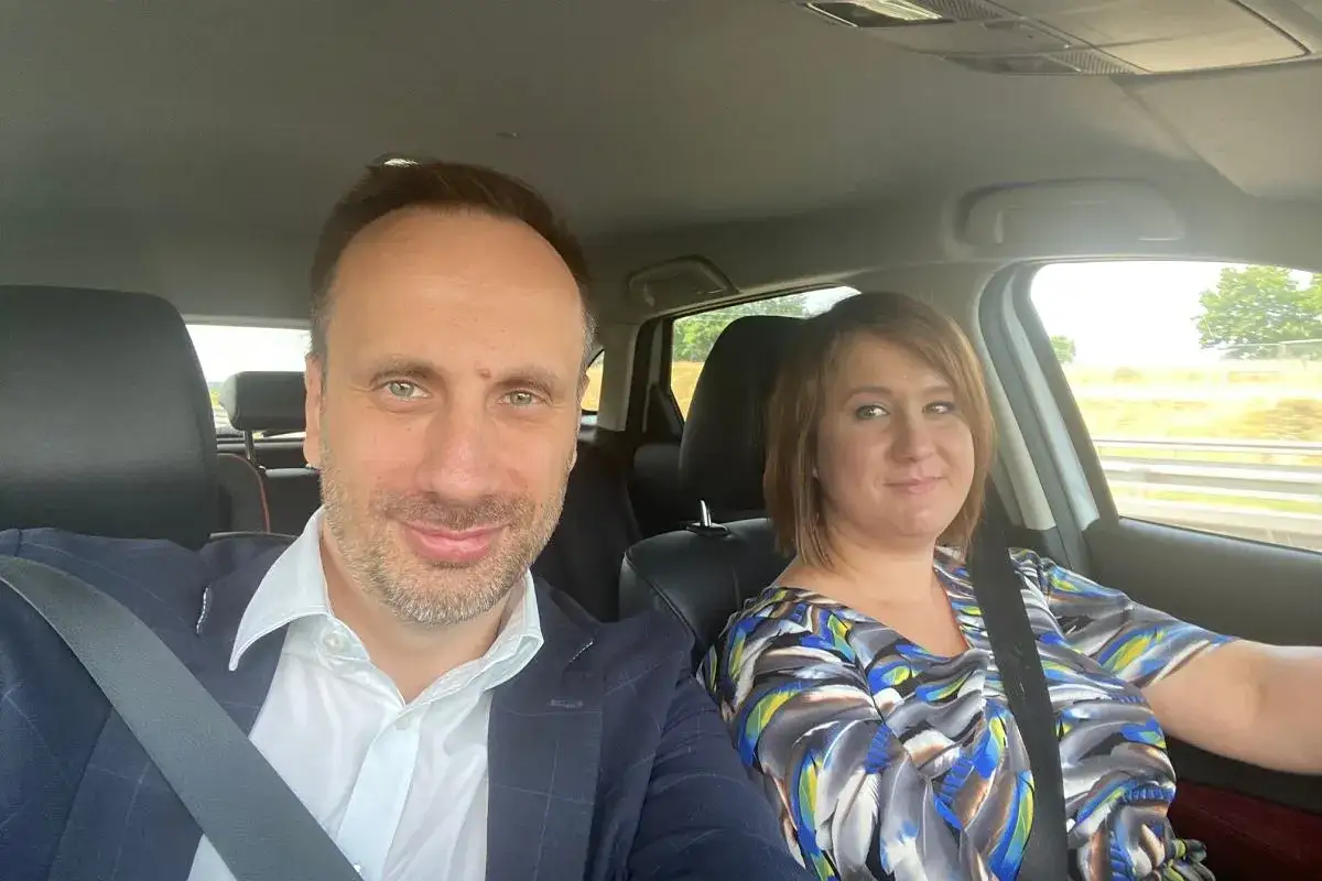 Janusz Kowalski z żoną w drodze z dziećmi na wakacje. Uśmiechnięci podróżują samochodem.