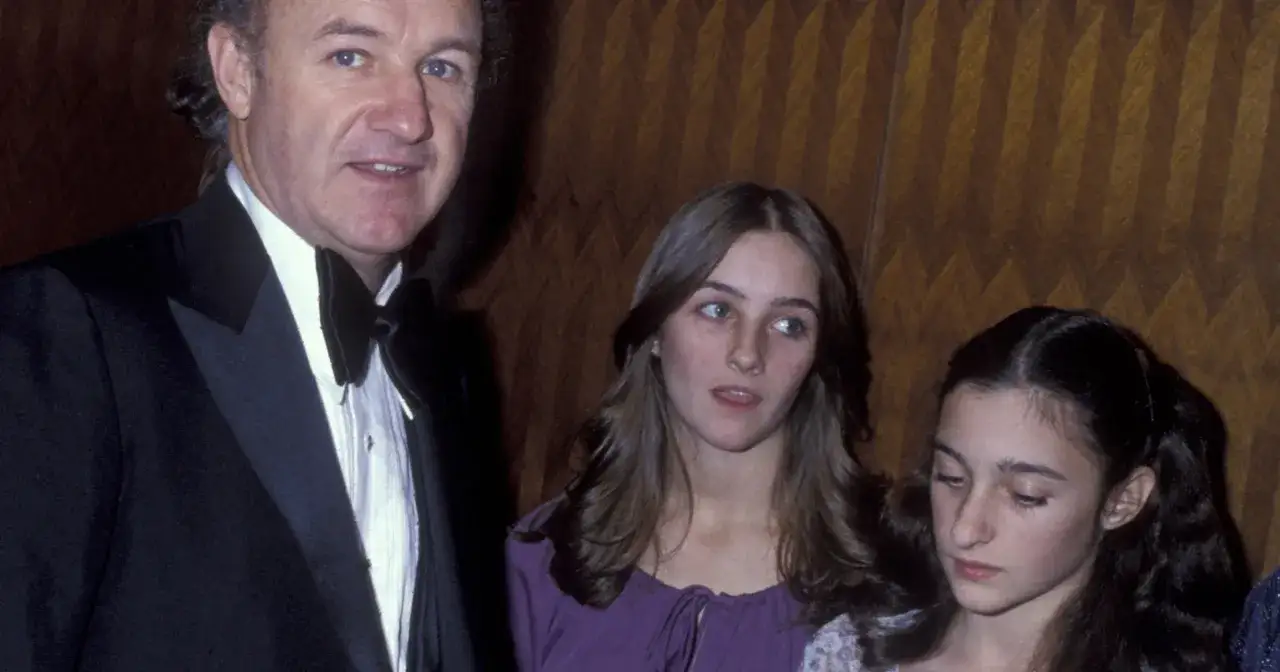 Gene Hackman w garniturze z dwoma młodymi dziewczynami, jego dzieci, podczas wydarzenia.