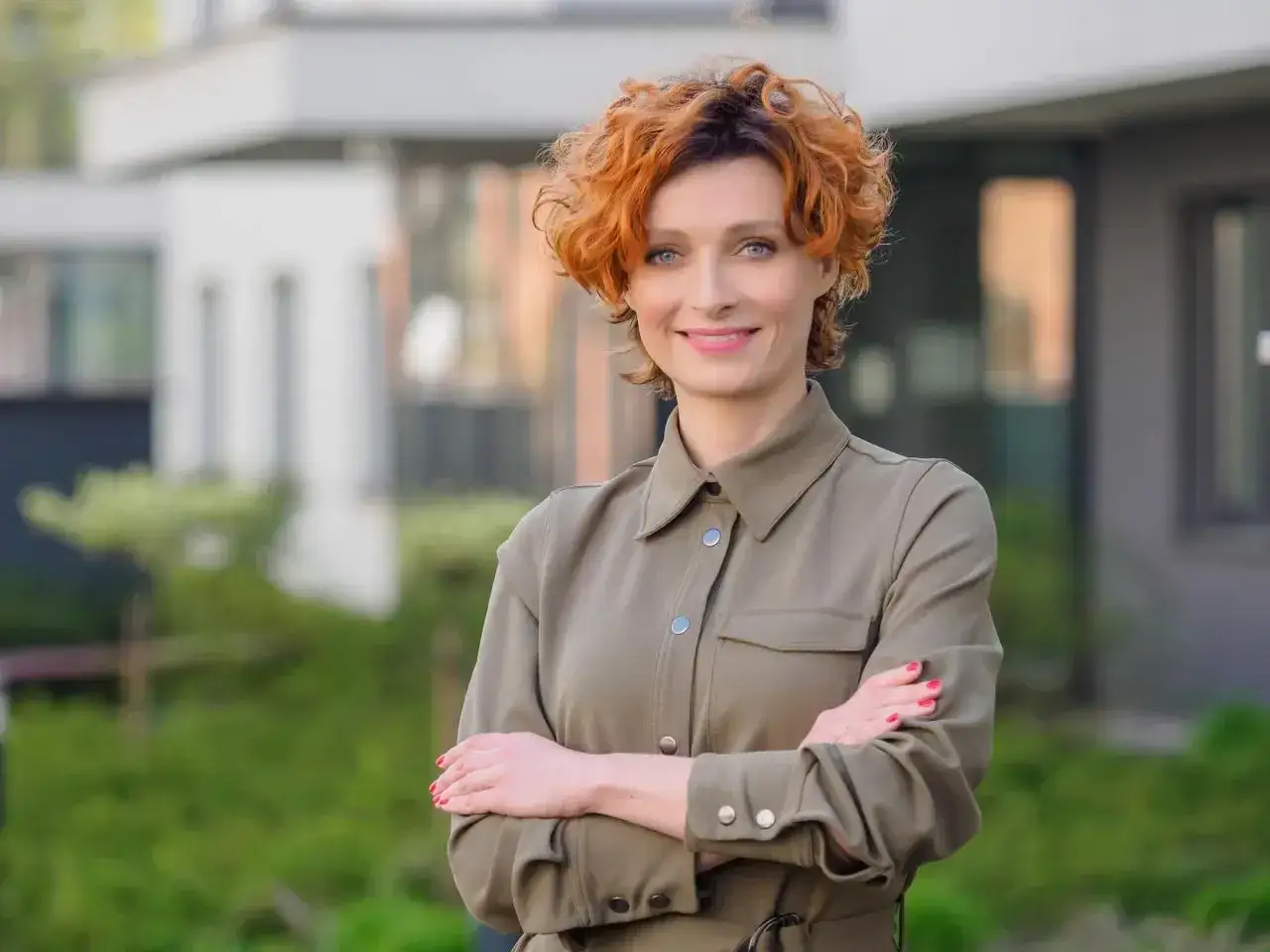 Katarzyna Jaroszyńska, z burzą rudych włosów i pewnym uśmiechem, prezentuje się elegancko w khaki sukience. Jej wiek dodaje jej doświadczenia i charyzmy.