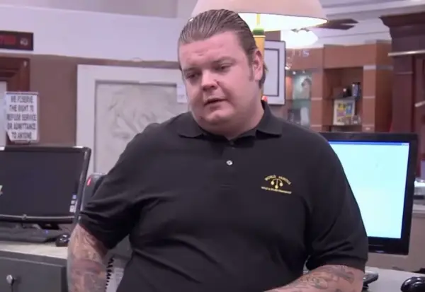 Corey Harrison nie żyje. Mężczyzna w czarnej koszulce z logo "World Famous" stoi przy ladzie.